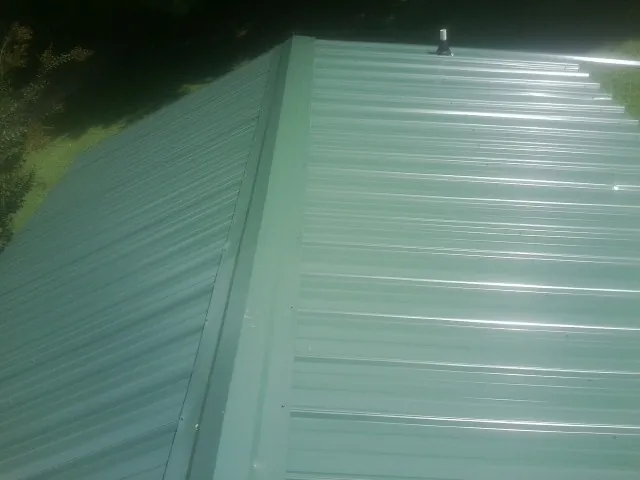 New green metal panels meeting at the ridge of a roof — Flat Roof Repair work by our crew in Sabine Pass