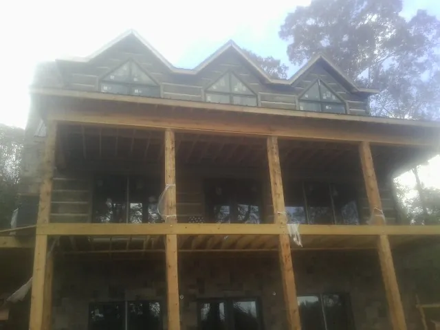 Dormers and porch framing on a large log home under construction — Roof Coating work by our crew in Sabine Pass