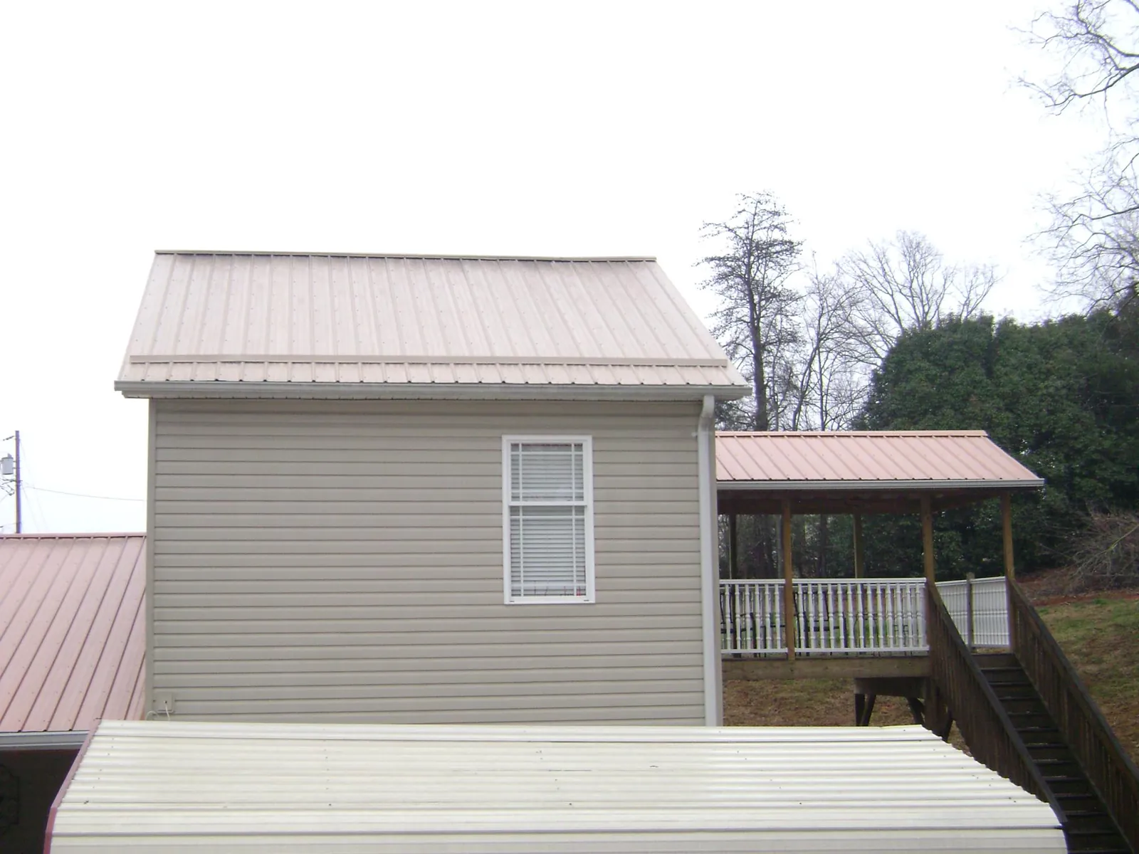 Tan metal roofs on a two story addition and attached porch, from a Roof Replacement job in Sabine Pass
