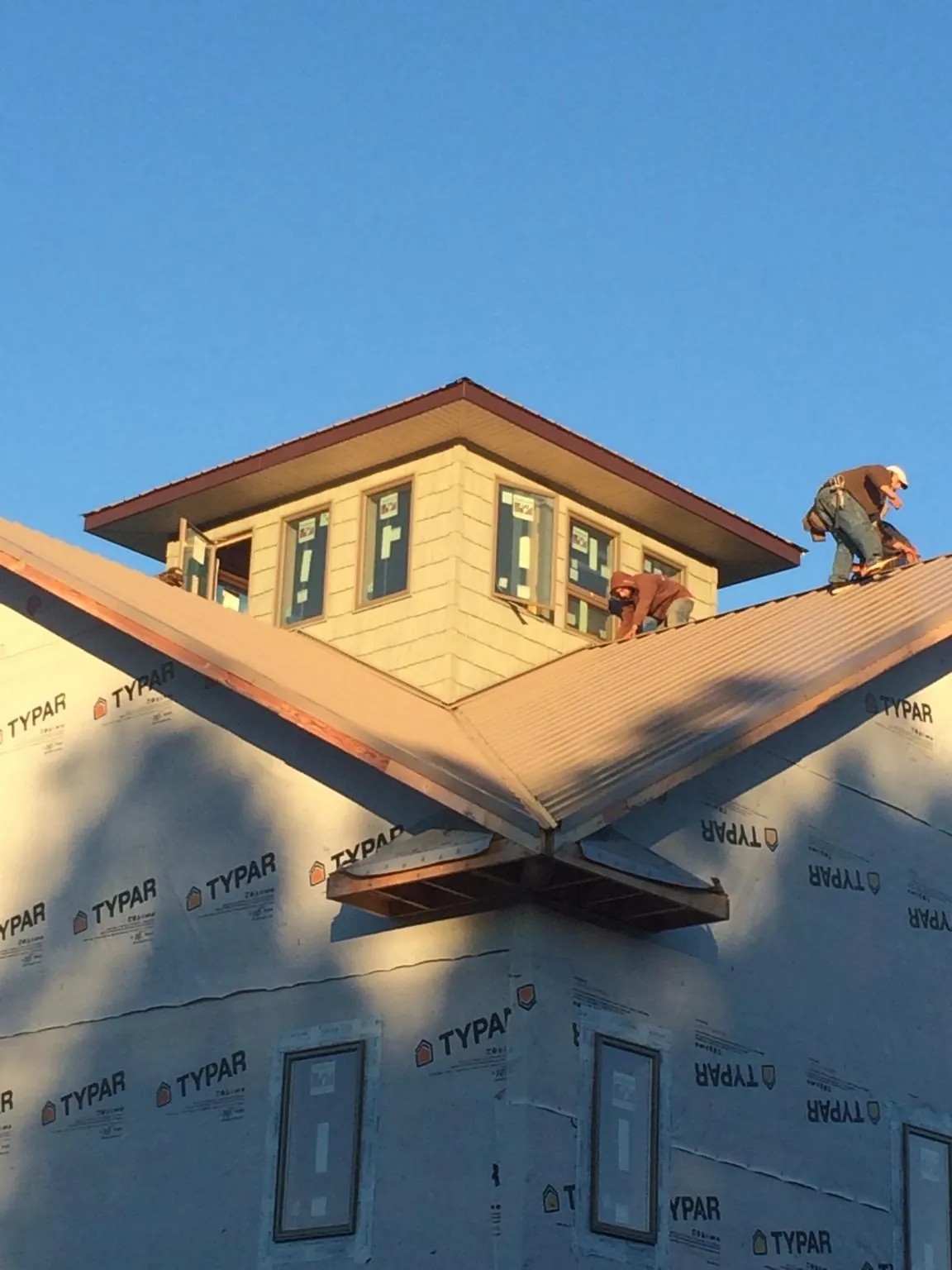 Roofers working around a rooftop cupola on a new metal roof at sunset — Roof Waterproofing in Sabine Pass by Roofing Brothers